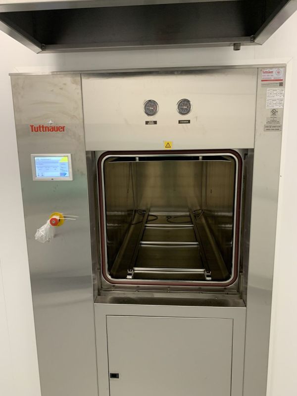 Tuttnauer 66E autoclave with the chamber door open, showing loading rails, touchscreen controls and pressure gauges, at Optimi Health